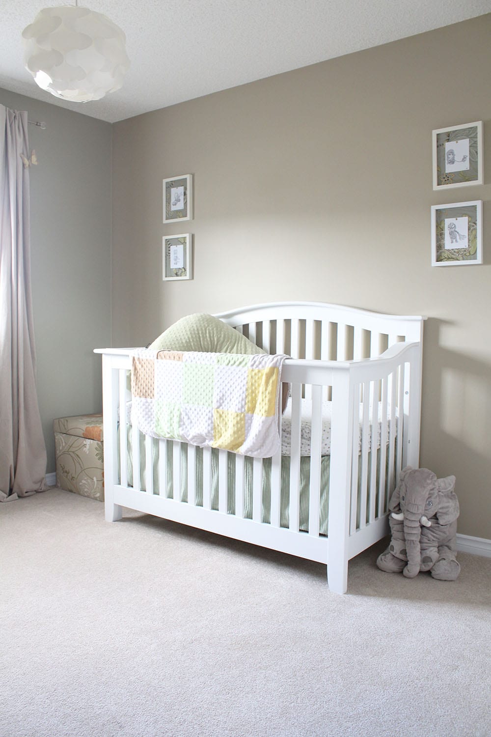 A neutral baby bedroom with a white crib and baby superhero art.