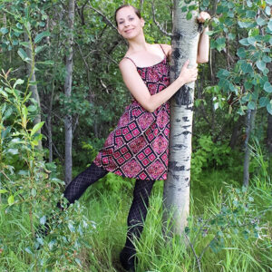 Larissa Swayze in a patterned dress hugging a tree.