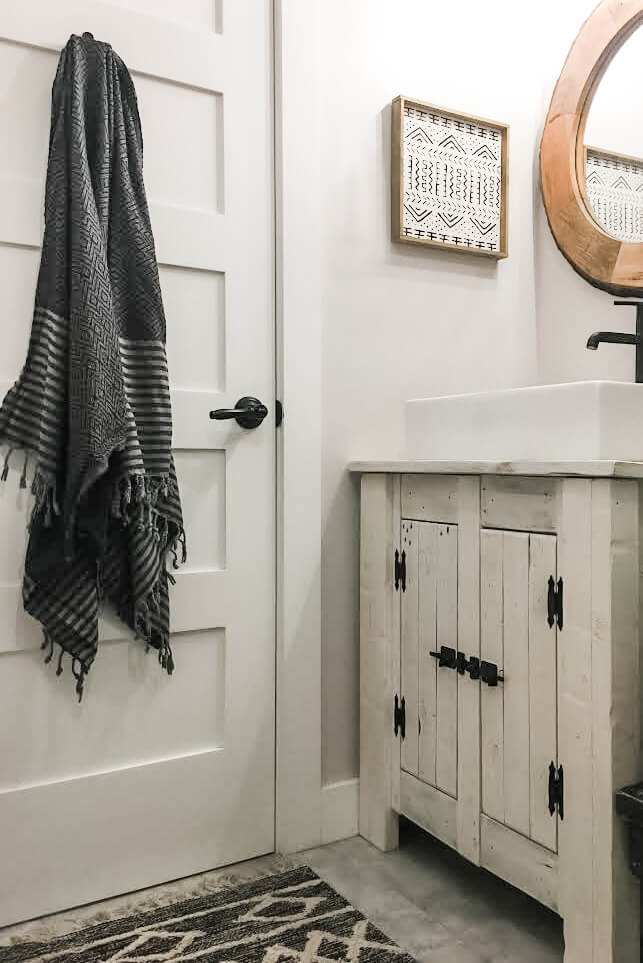 A white bathroom with natural wood and black accents.