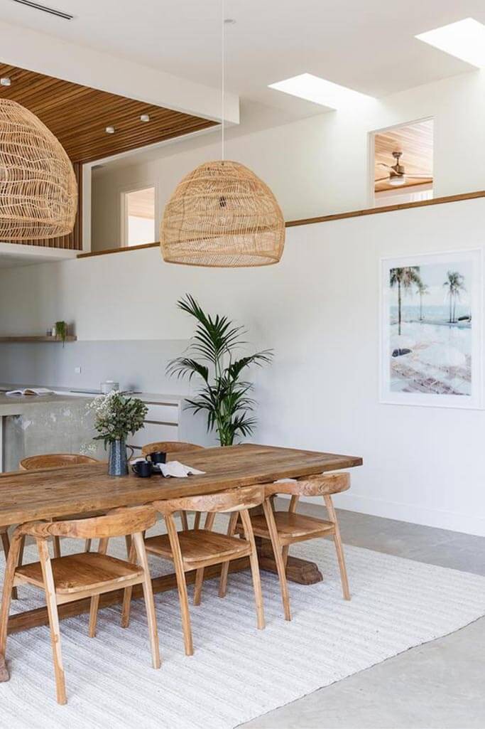 A dining area with a rustic table and large woven pendant lights.