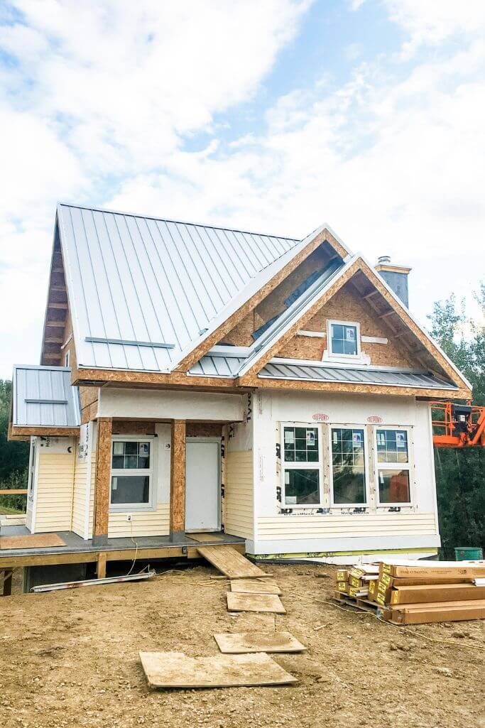 An under-construction home with yellow siding and metal roofing.