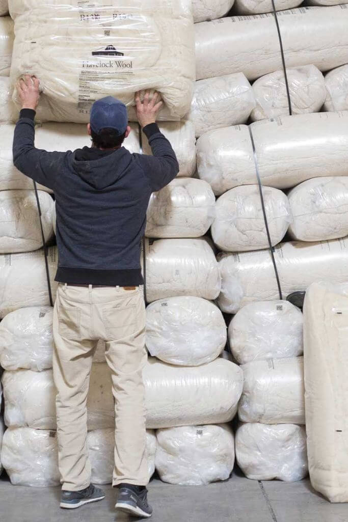 A man stacking wool insulation in a pile.