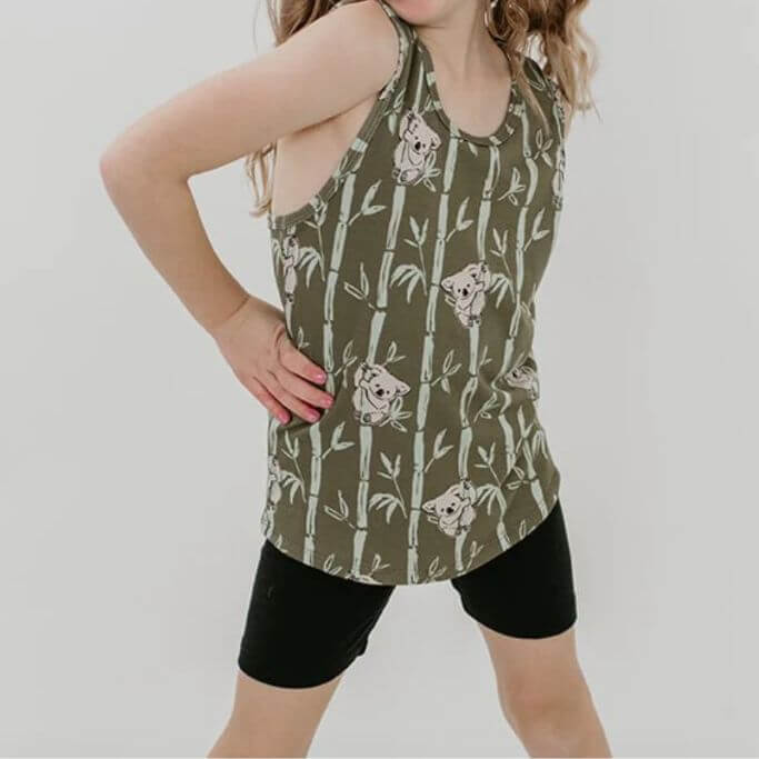 A child wearing black shorts and a tank with koalas on it.