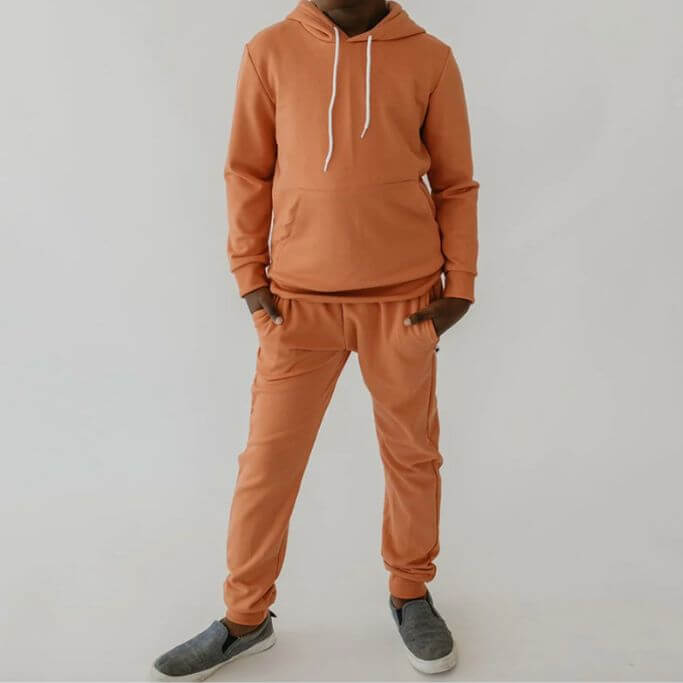 A child wearing an orange hoodie and matching sweatpants.