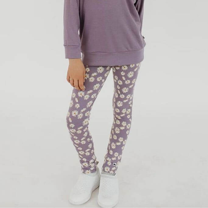 A child wearing purple floral leggings and a purple sweater.