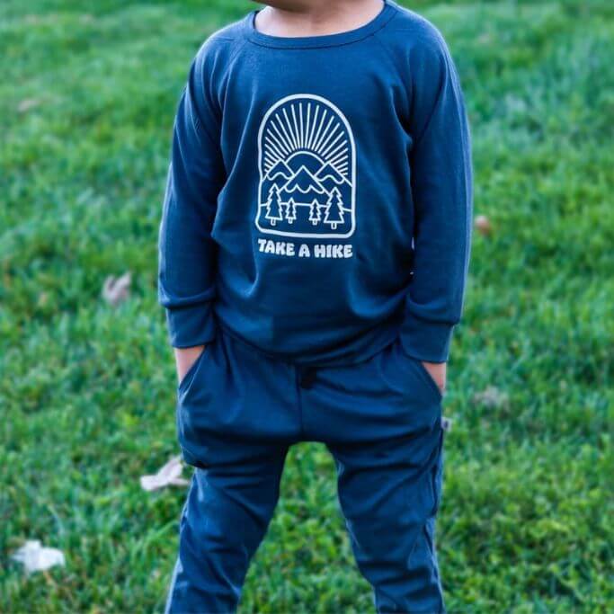 A child wearing a dark blue sweater with text take a hike on it.