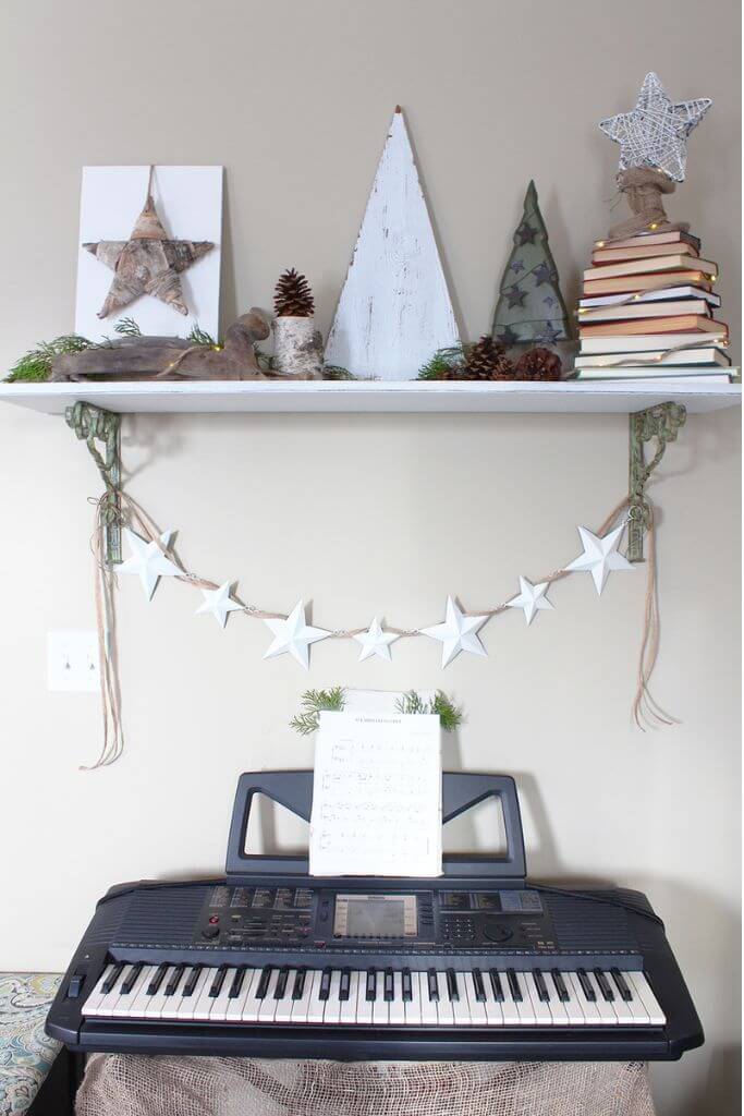 A piano keyboard beneath a shelf decorated with rustic holiday decor.