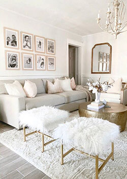 A glam-inspired living room with off-white furniture, framed black and white photos and gold accents.