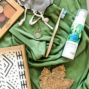 Various products such as a bamboo toothbrush, a necklace and a cork maple leaf sitting on a green fabric background. Click to visit post.