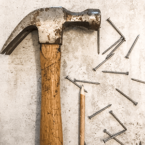 A hammer and nails sitting on a concrete tile floor. Click to visit post.