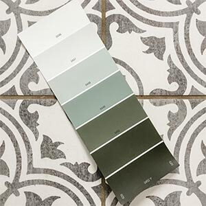 A paint sample featuring green colours sitting on a patterned tile floor. Click to visit post.