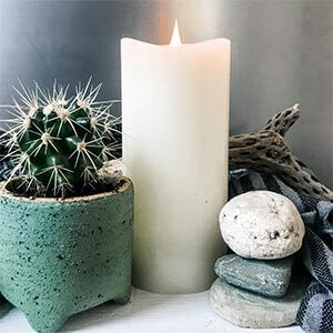 A candle sitting next to a pile of rocks and a small cactus. Click to visit post.