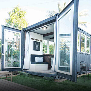 A white and black shipping container home with the doors wide open.