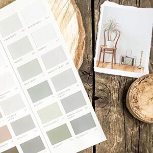 A paint sample booklet on a rustic wood background next to a photo of a wooden chair.