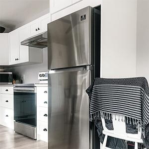 A stainless steel fridge in a white kitchen with black accents.