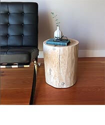 A light wood stump used as a side table next to a leather couch.