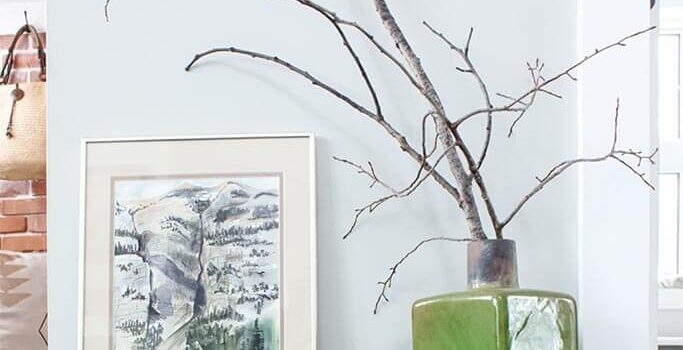 A rustic side table with nature-inspired artwork and decor on top.