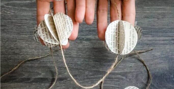 A closeup of a pair of hands holding a garland made of book page orbs and twine.