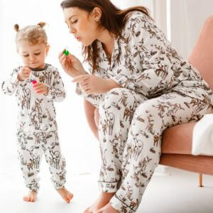 A woman and child wearing matching pajamas playing with bubbles.