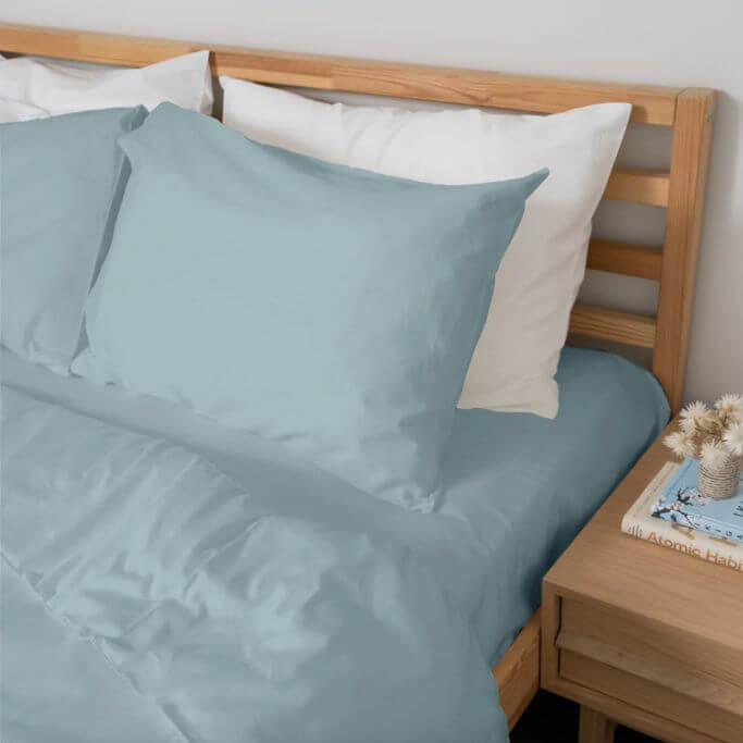 Light blue-green bedding on a simple wood bed frame.