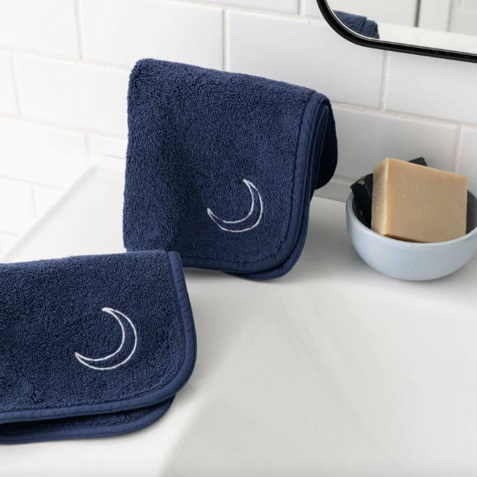 A pair of navy blue makeup towels sitting on the edge of a sink.