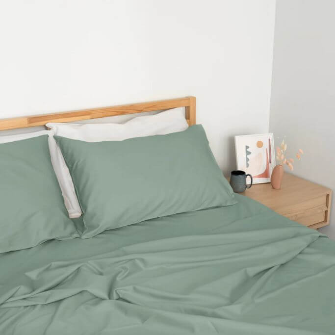 Soft green bedding on a simple wood bed frame.