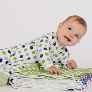 A baby in polka dot pajamas laying on a pile of blankets.