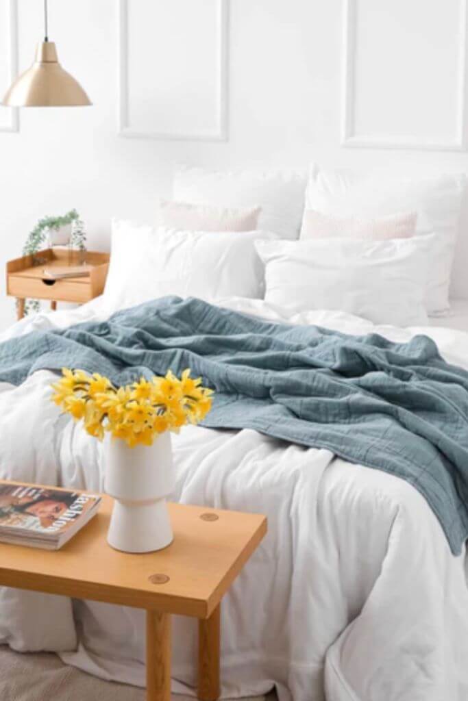 A bright bedroom with white bedding and blue and yellow accents.