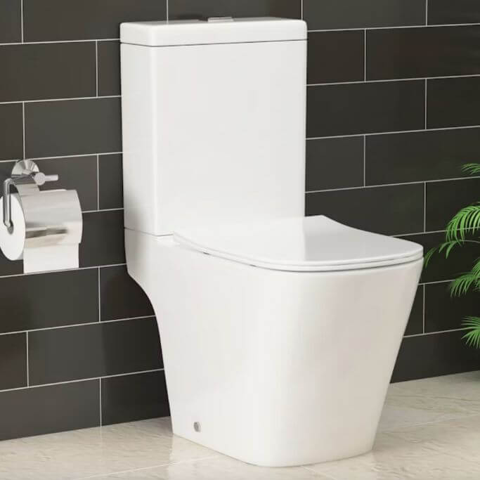 A white toilet in a bathroom with a dark grey tiled wall and cream tiled floors.