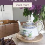 A wooden dining table set with a cream coloured runner and fresh lilacs with text 5 tips for choosing rustic farmhouse table decor.