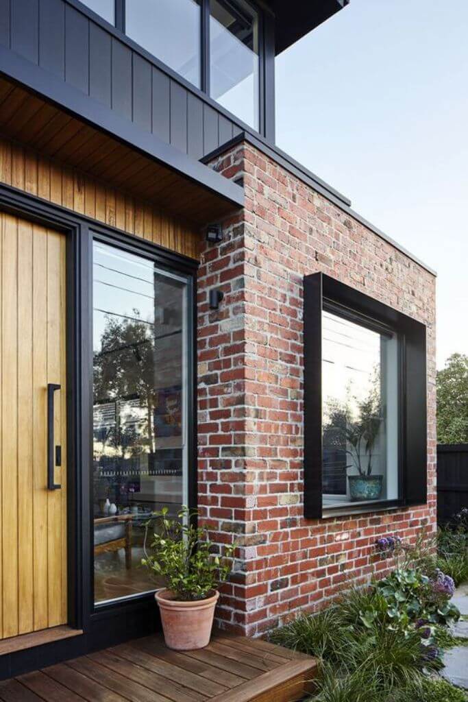 A modern home exterior with reclaimed brick and black window frames.