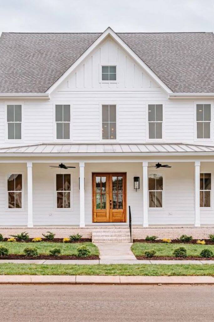 A large white farmhouse-style home with a wooden door.