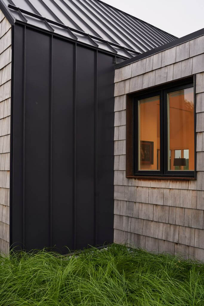 A modern home with a mix of black metal and grey cedar siding.