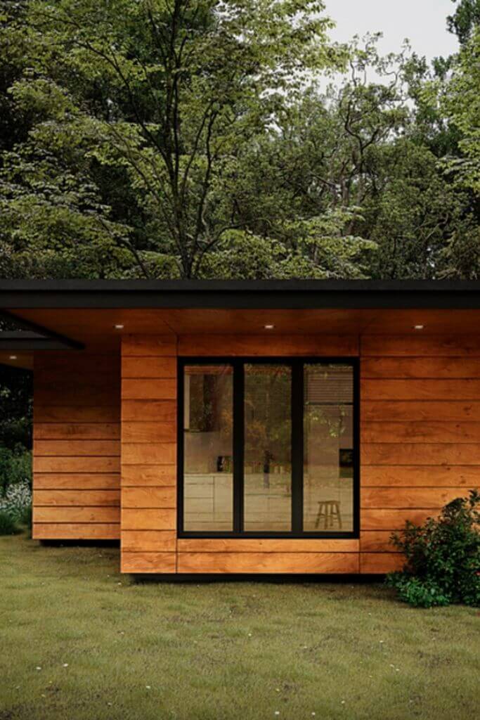 A house with medium-toned wood siding in front of a large tree.