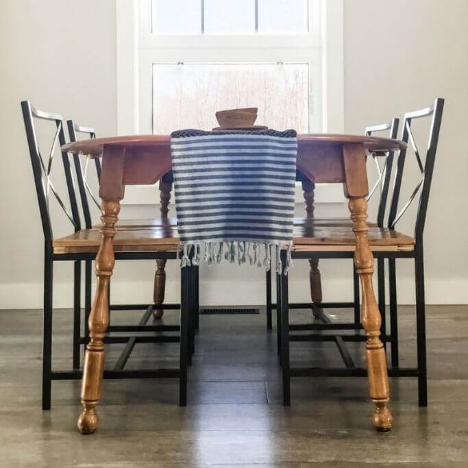 A wooden table with four metal and wood chairs in front of a window.