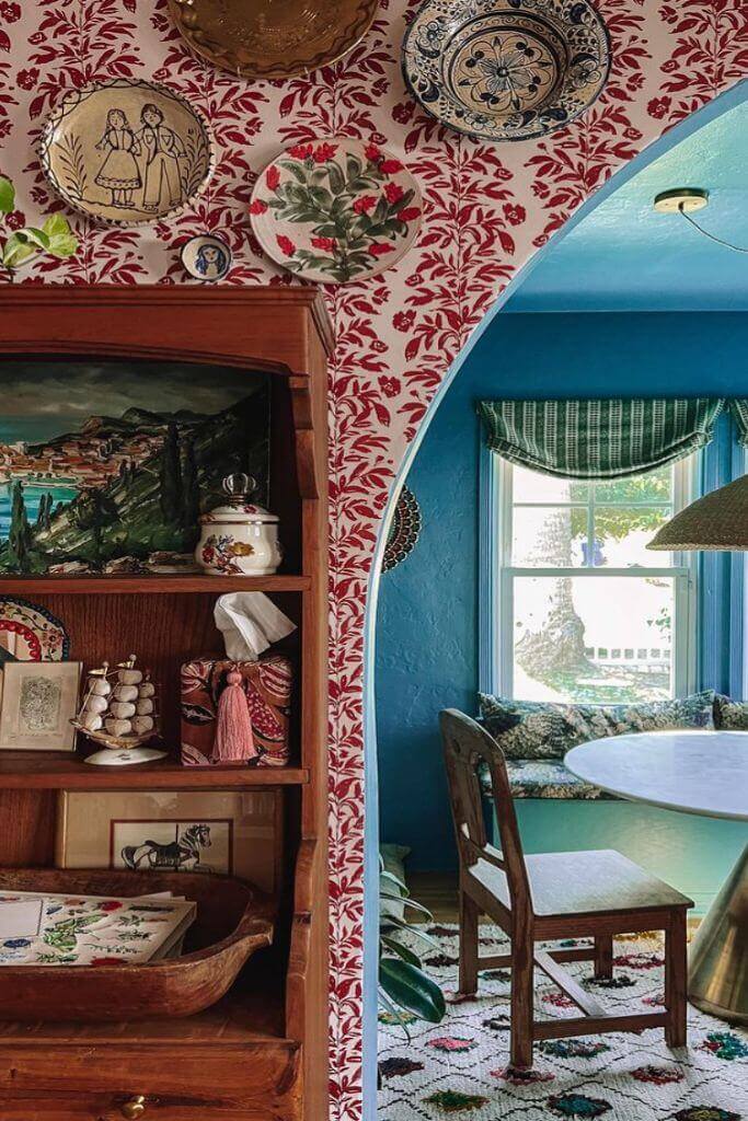 A bright blue kitchen with contrasting red floral wallpaper.