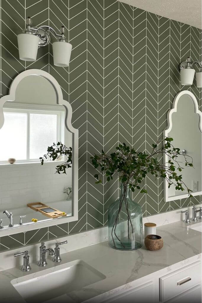 A bathroom vanity with green herringbone wallpaper behind it.