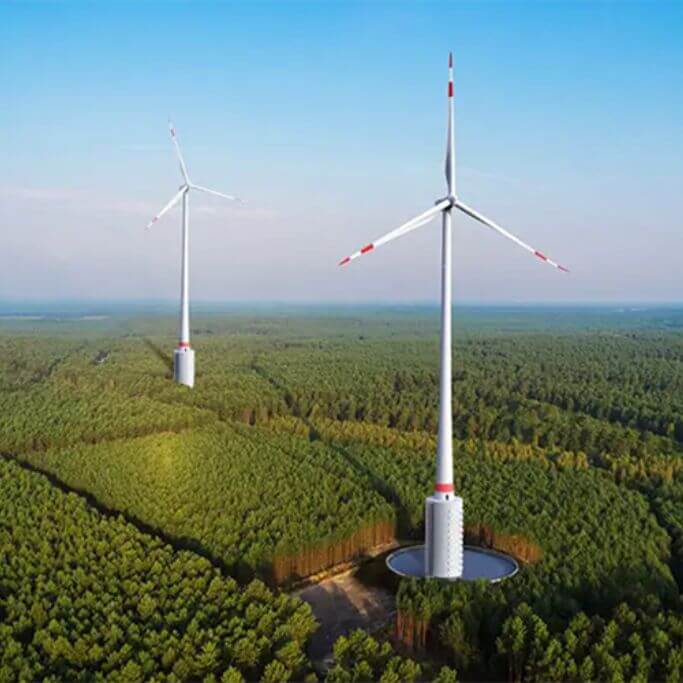 Two large wind turbines in a green field.