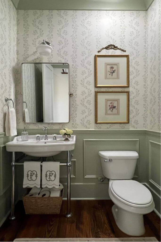 A bathroom with green panelling and neutral coloured floral wallpaper.