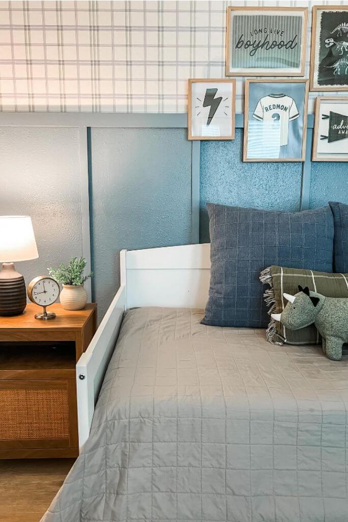 A kid's bedroom with blue and green accents and plaid wallpaper.