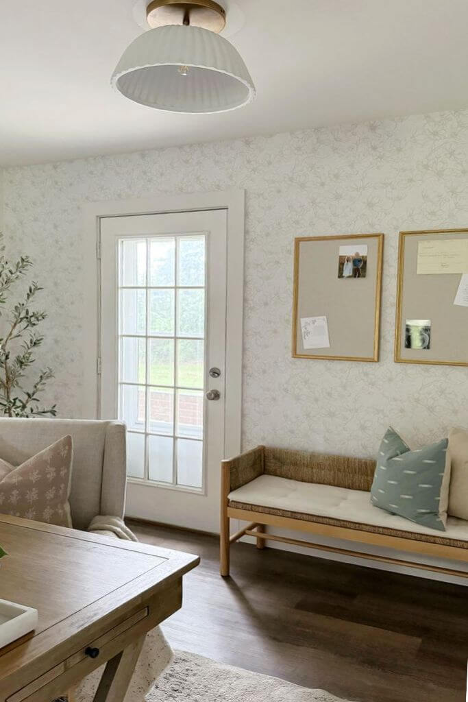 An interior door next to a wooden bench with floral wallpaper on the walls.