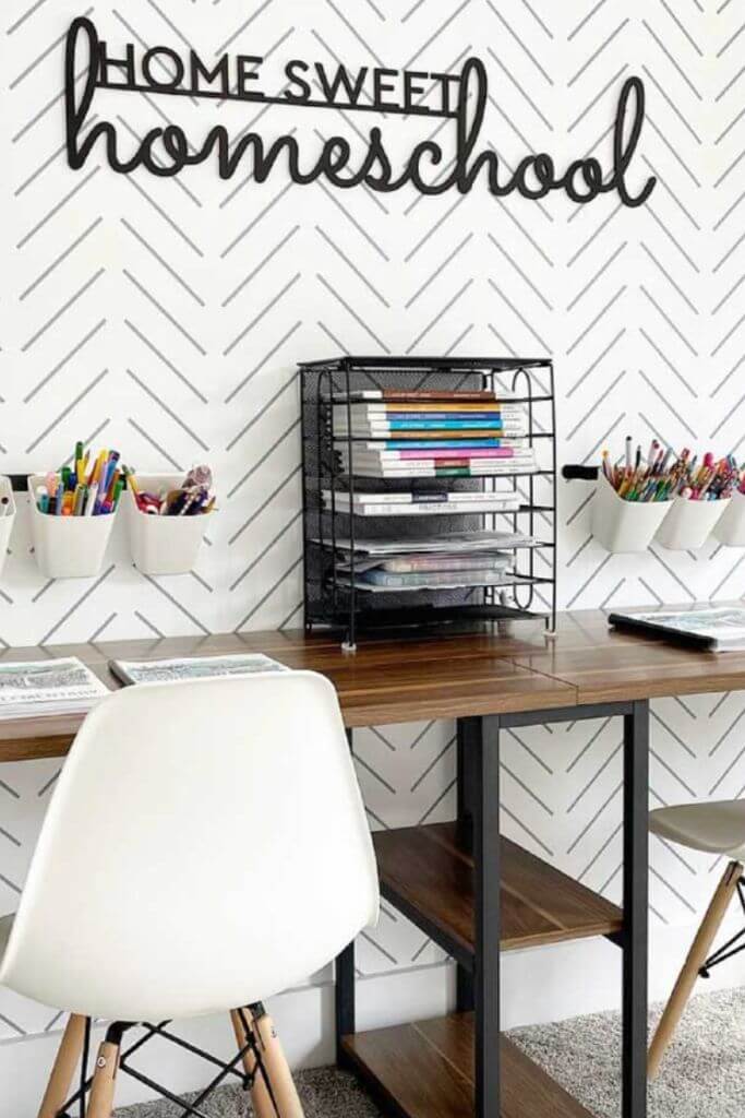 A home office with black and white wallpaper and a sign that reads home sweet homeschool.