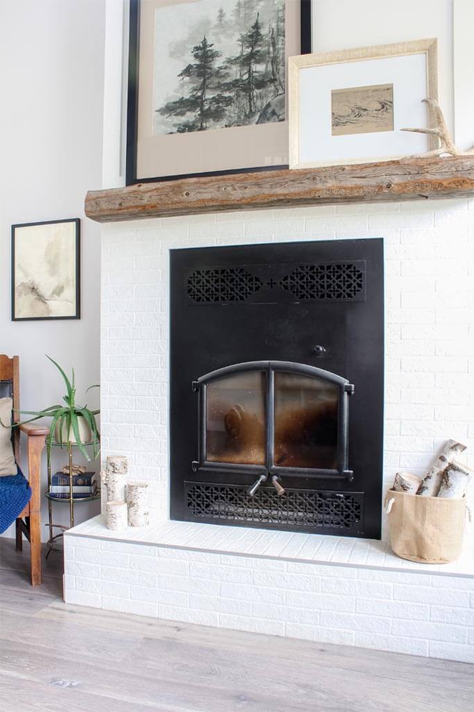 A white brick fireplace decorated with nature inspired decor.