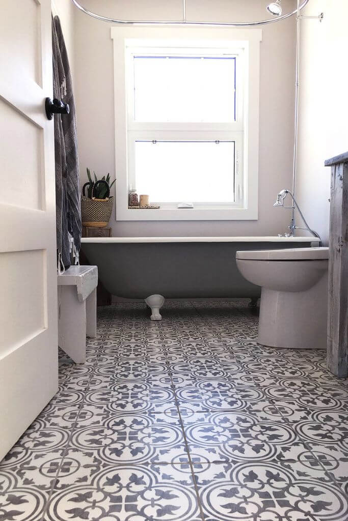 A bathroom with a clawfoot tub and grey and white patterned tile.