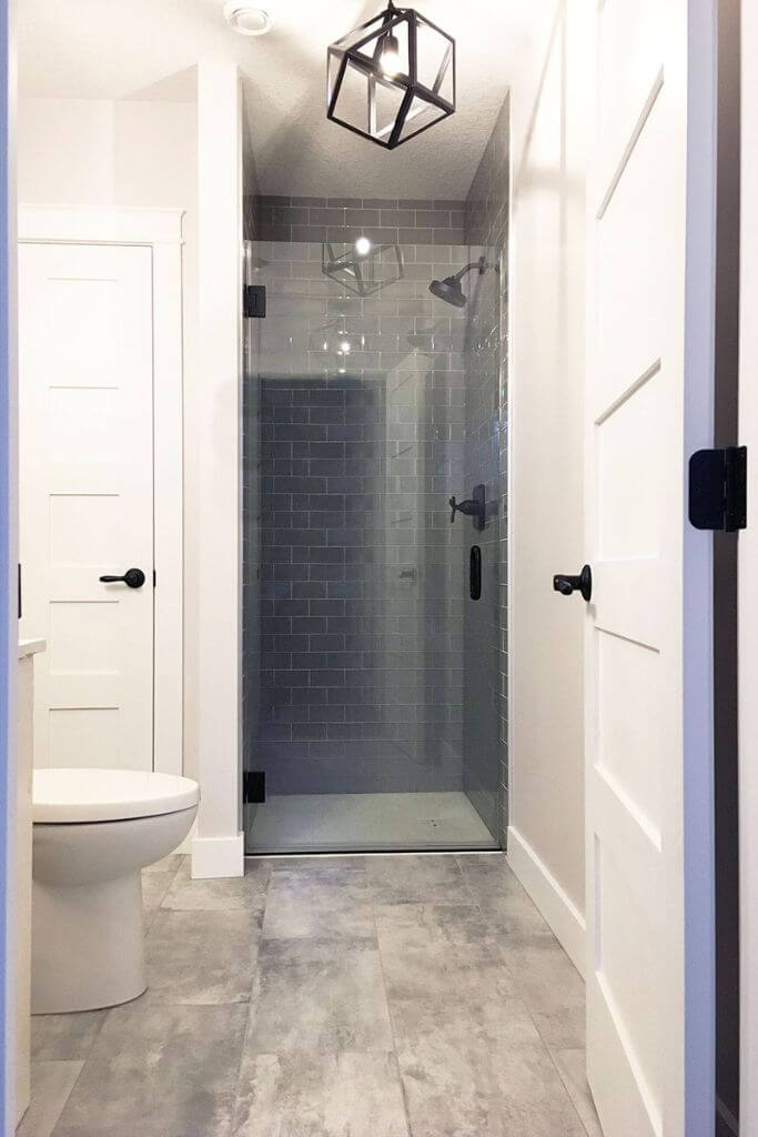 A bathroom with a glass shower and grey tiled floors.