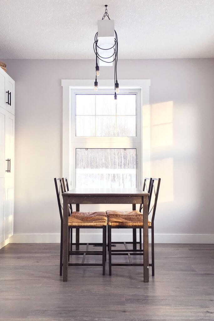 A dining room with a small wooden table and a large window.