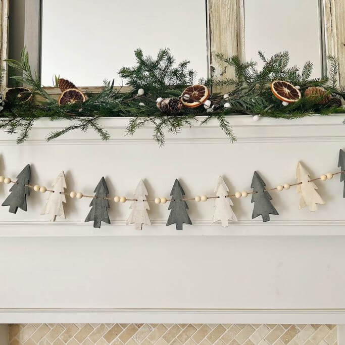 A fireplace mantel decorated with a Christmas tree garland.