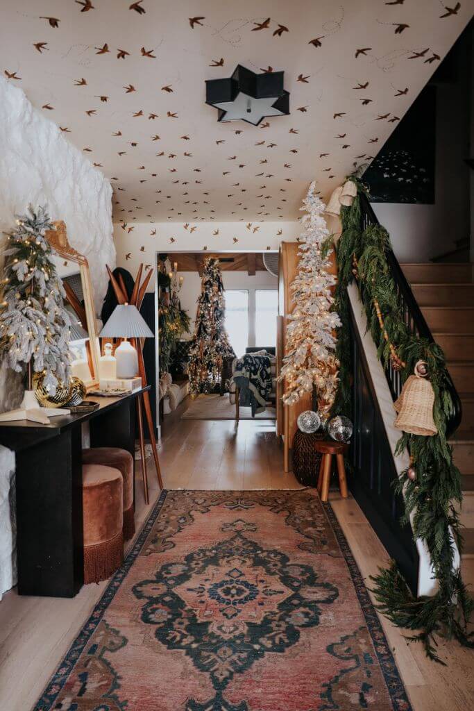 A front entry of a home decorated for Christmas with lots of layers of greenery and ornaments.