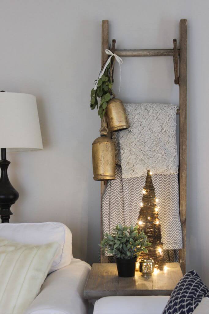 A wooden ladder with blankets hanging on it as well as a rustic bell.