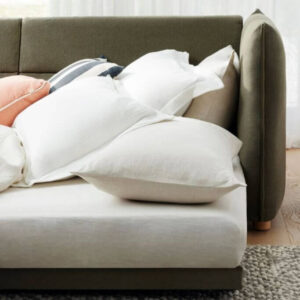 Closeup of a dark green sleeper sofa pulled out in a brightly lit living space.